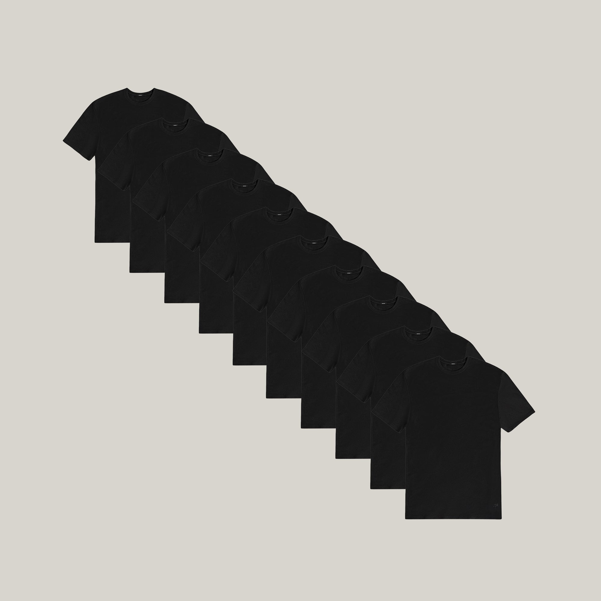 Stack of black t-shirts on a light gray background model Tyler in All-Black