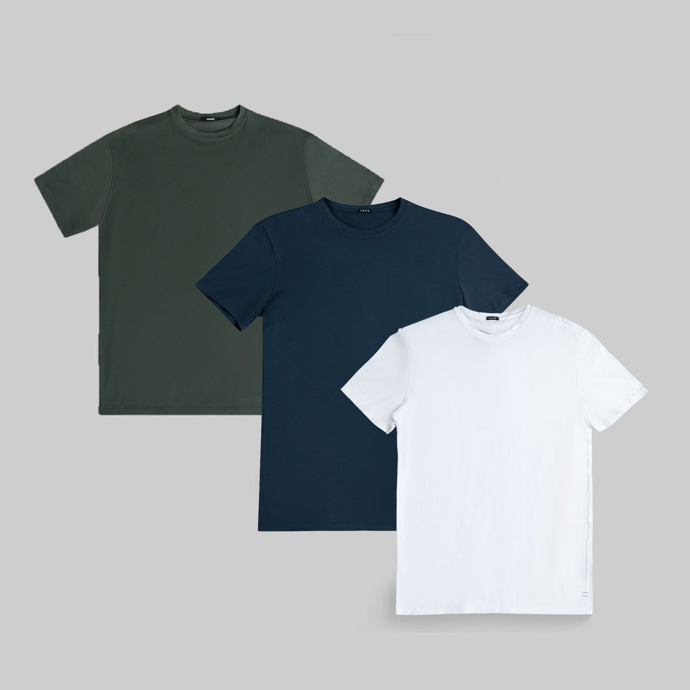 Three plain t-shirts in green, navy, and white on a gray background.