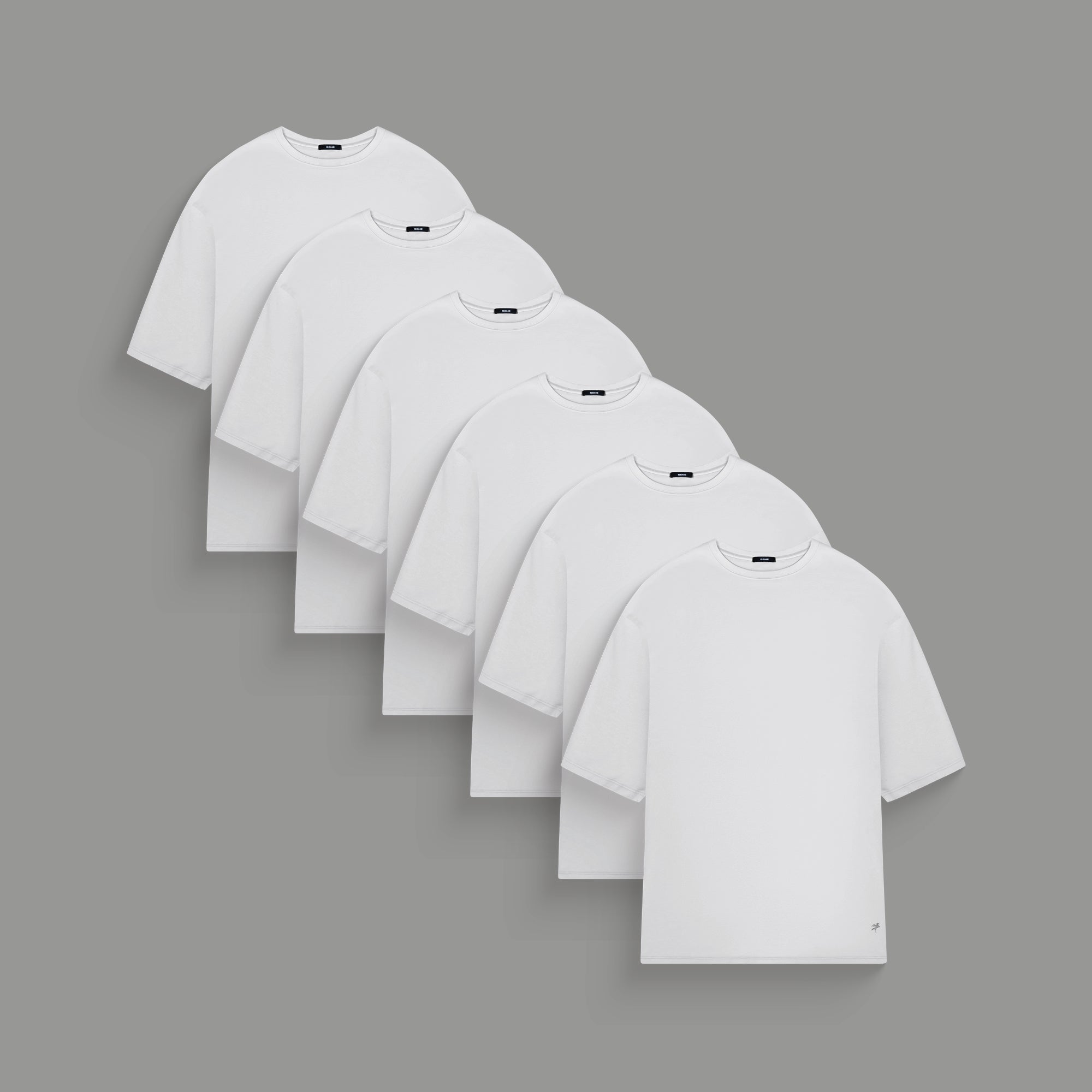 Three plain t-shirts in black, blue, and white on a gray background.
