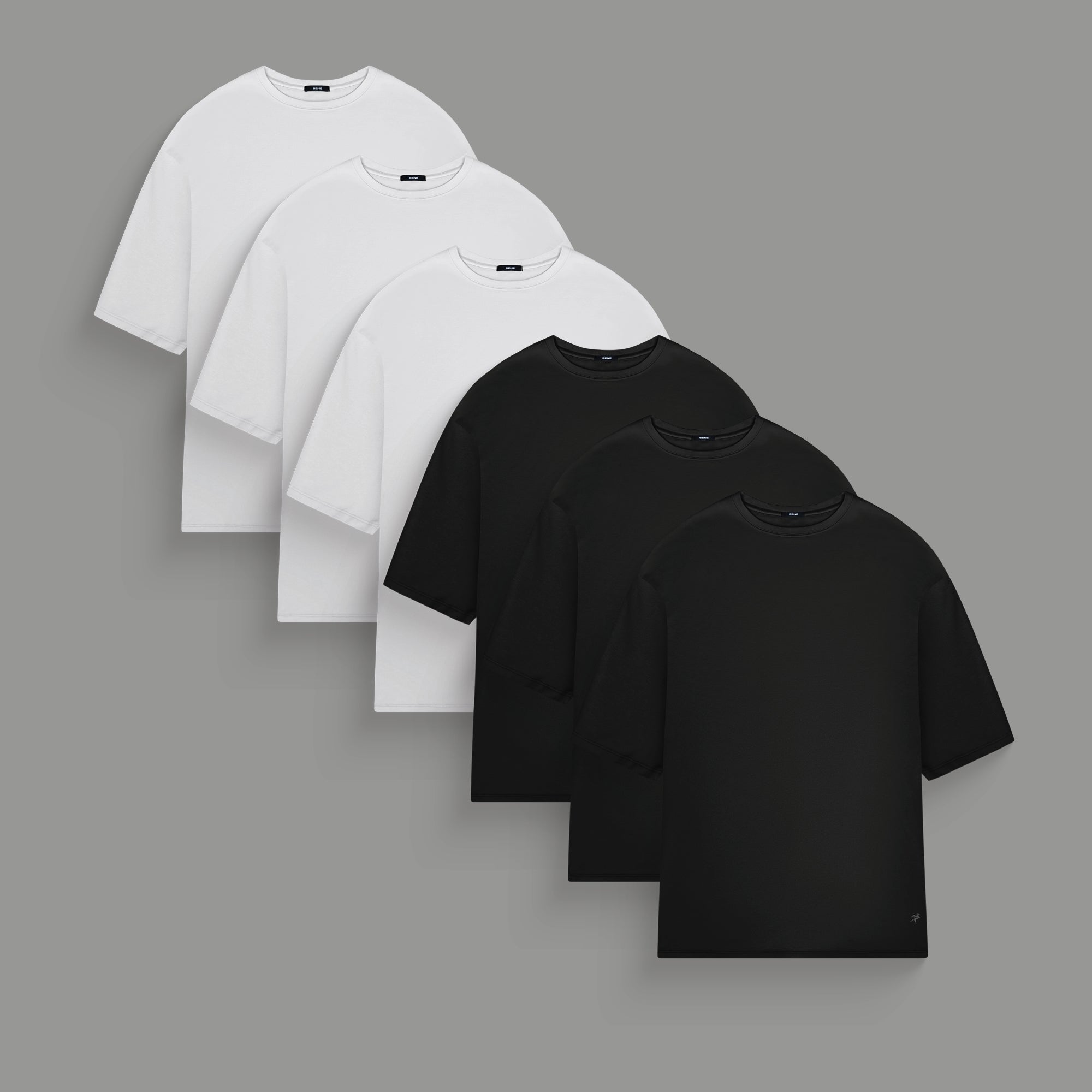 Three plain t-shirts in black, blue, and white on a gray background.