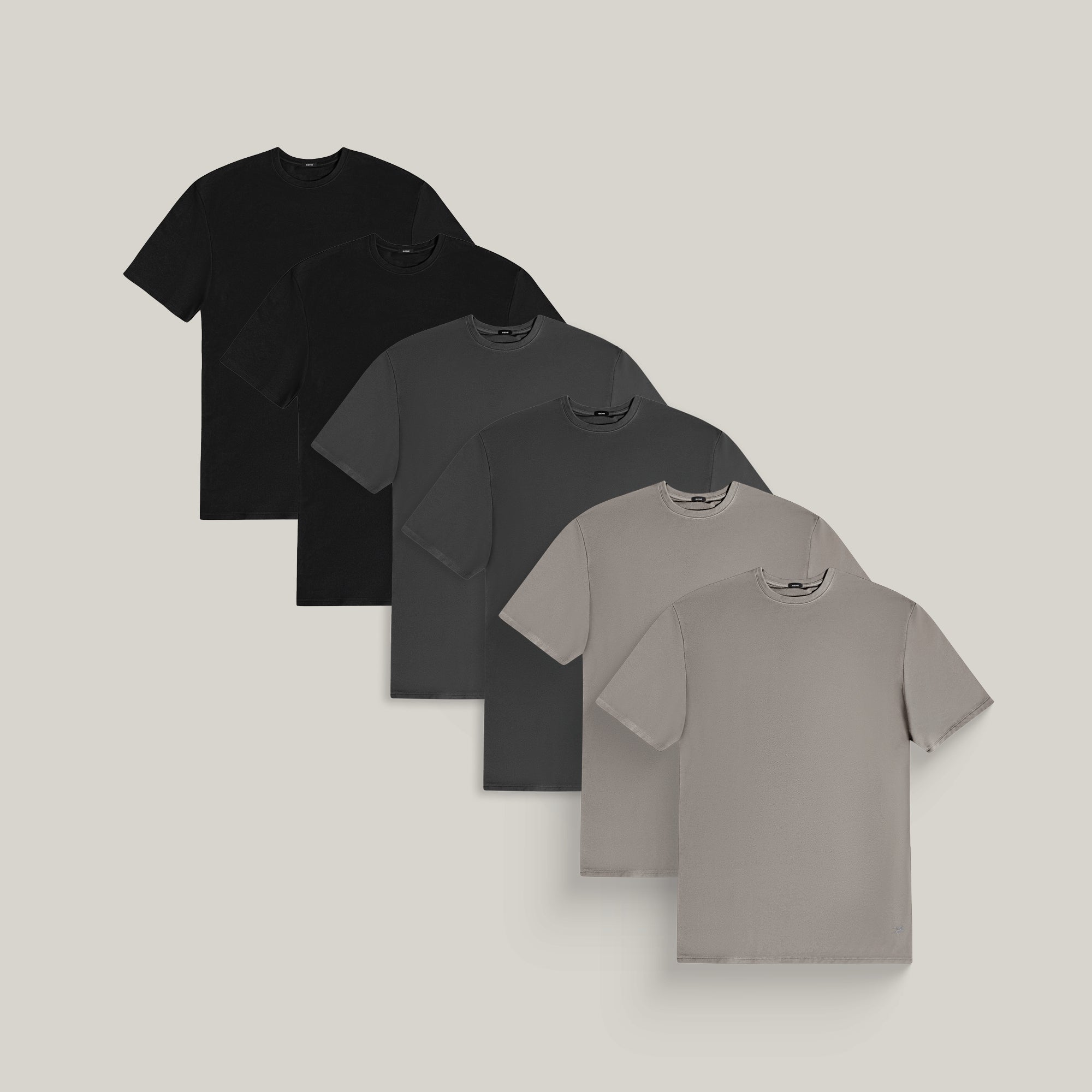 Six t-shirts in Black, Smoke and Frost Gray on a beige background model Tyler in Evening