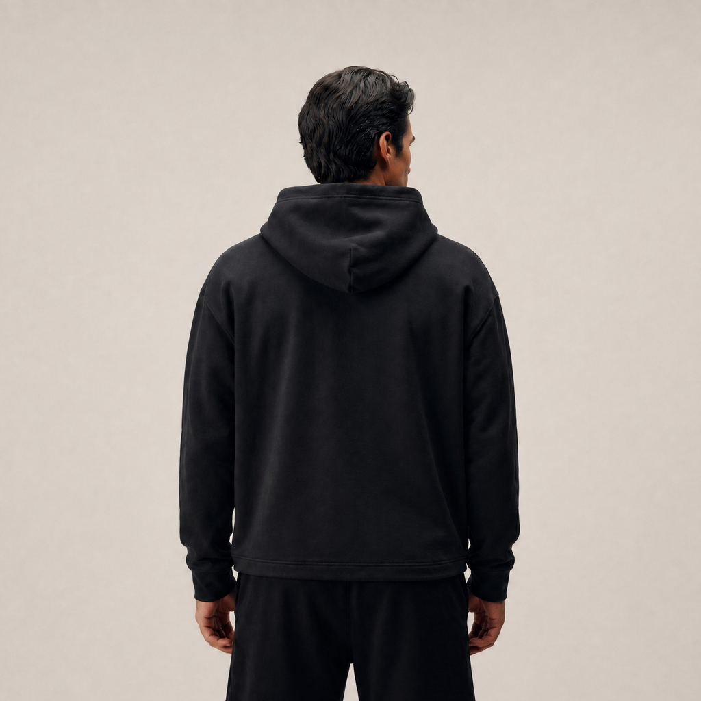 Person wearing a black hoodie and shorts on a beige background model Kive in black
