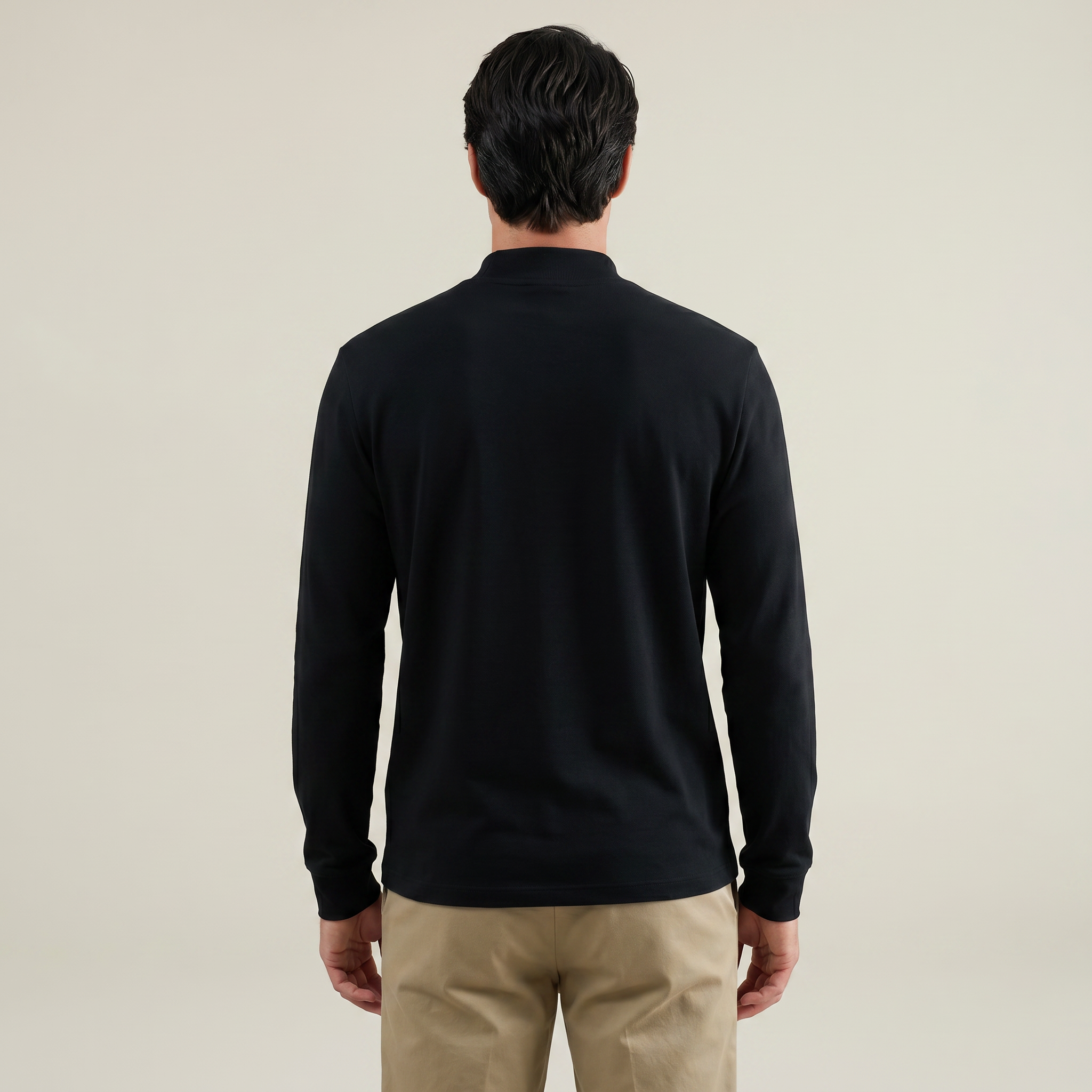 Man wearing a black long-sleeve shirt and beige pants on a beige background model kive in black