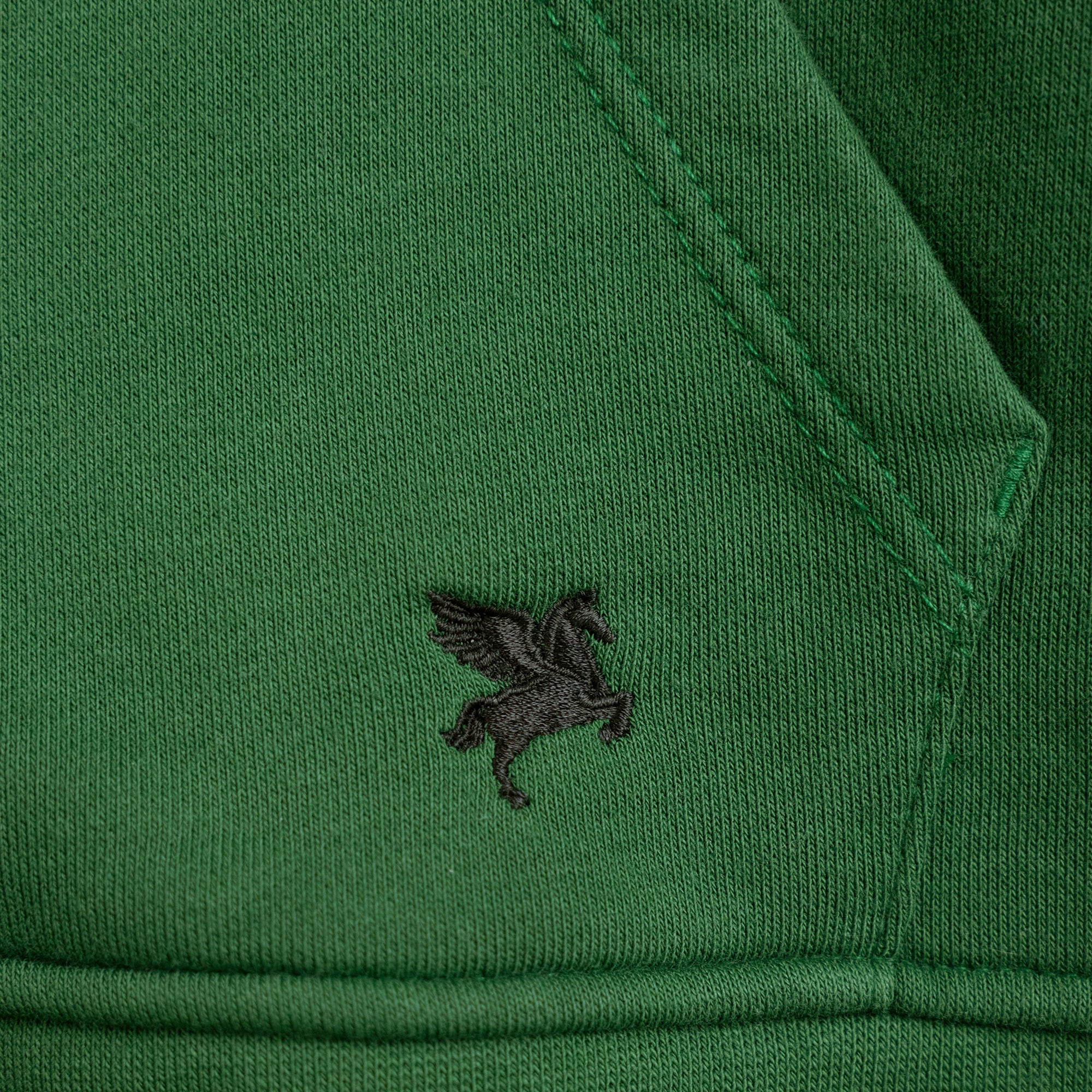 Close-up of a green garment with a small logo on the sleeve model Kive in eden