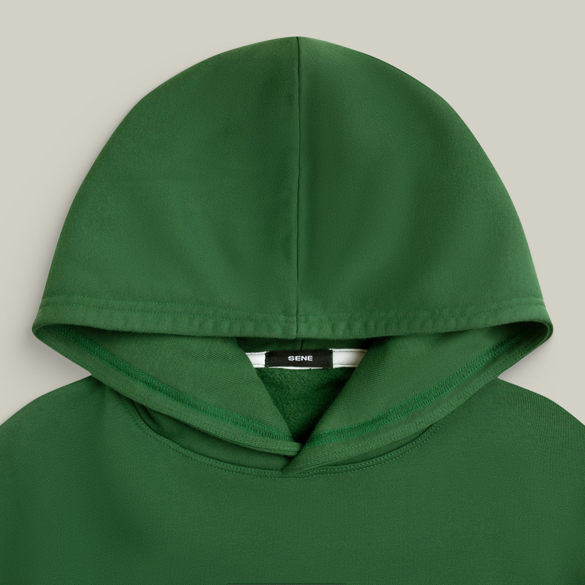 Green hoodie with a brand label on a light gray background model Kive in Eden