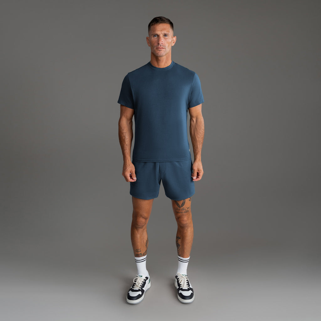 Six t-shirts in Black, Deep Sea, Moss, Umber, Frost Gray, and White on a beige background model Tyler in Best-Seller