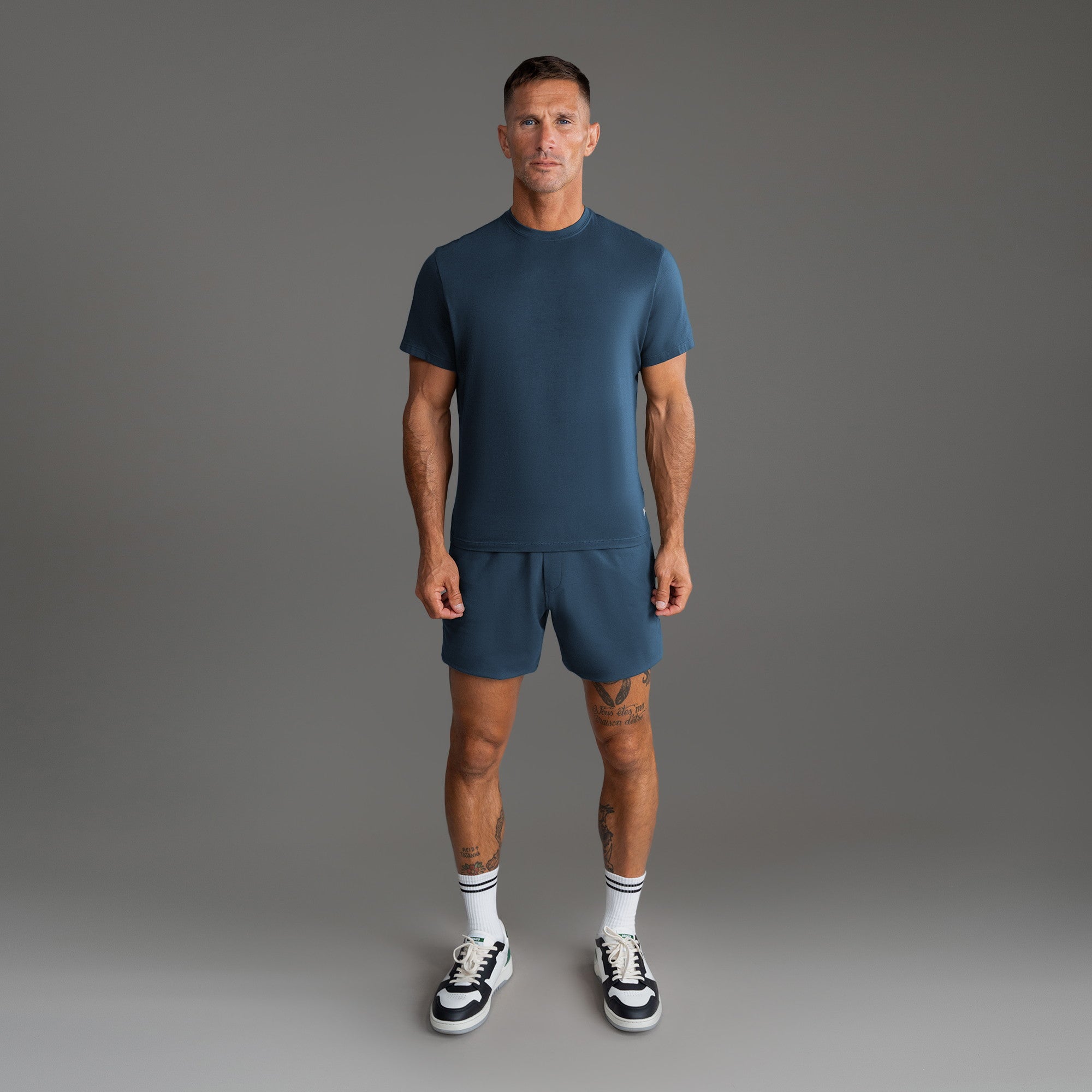 Six t-shirts in Black, Deep Sea, Moss, Umber, Frost Gray, and White on a beige background model Tyler in Best-Seller