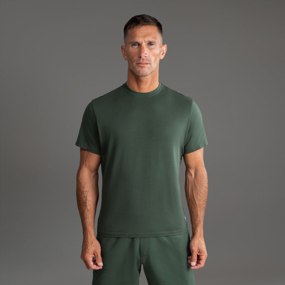 Person wearing a green t-shirt and pants against a gray background.
