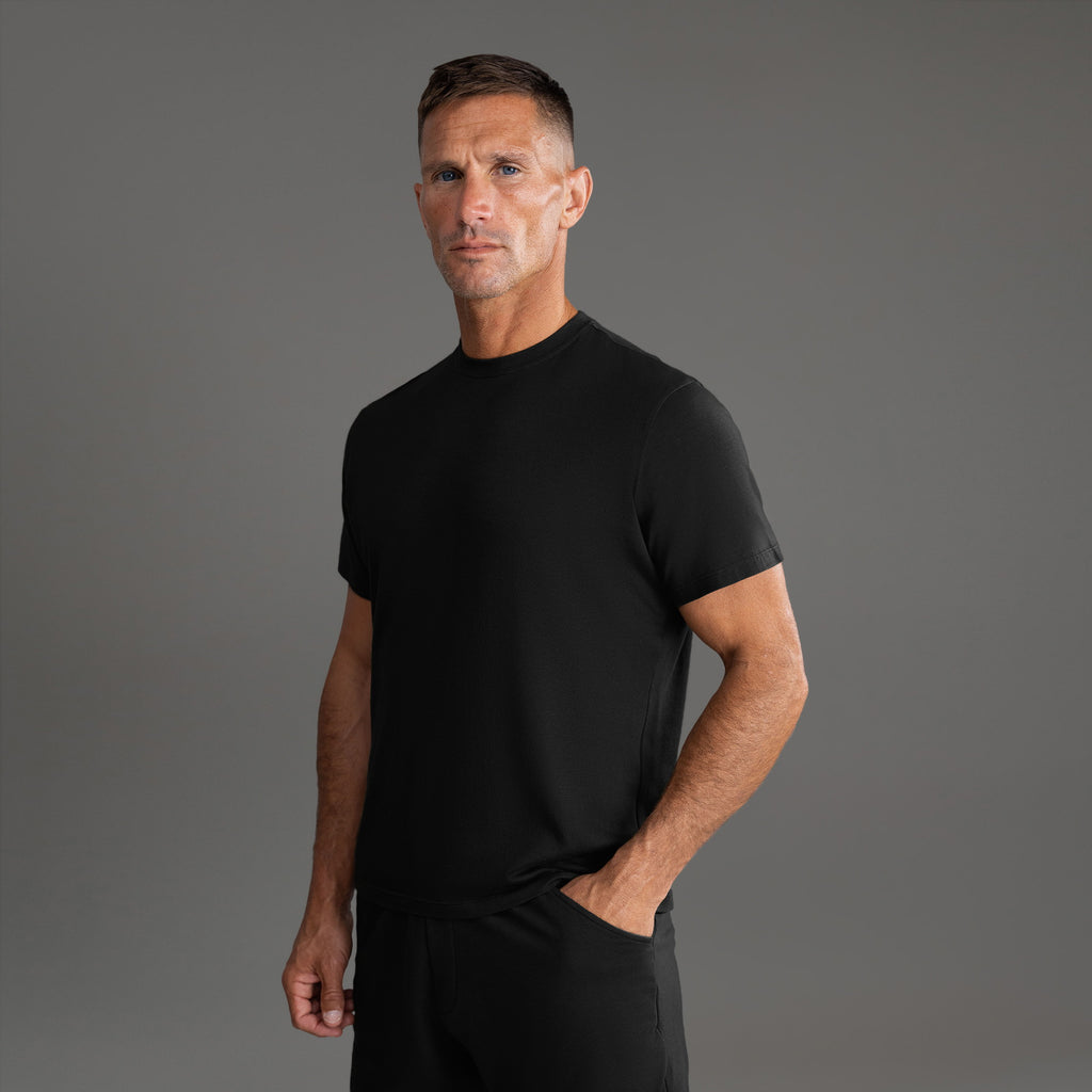 Six t-shirts in Black and White on a beige background model Tyler in Essential