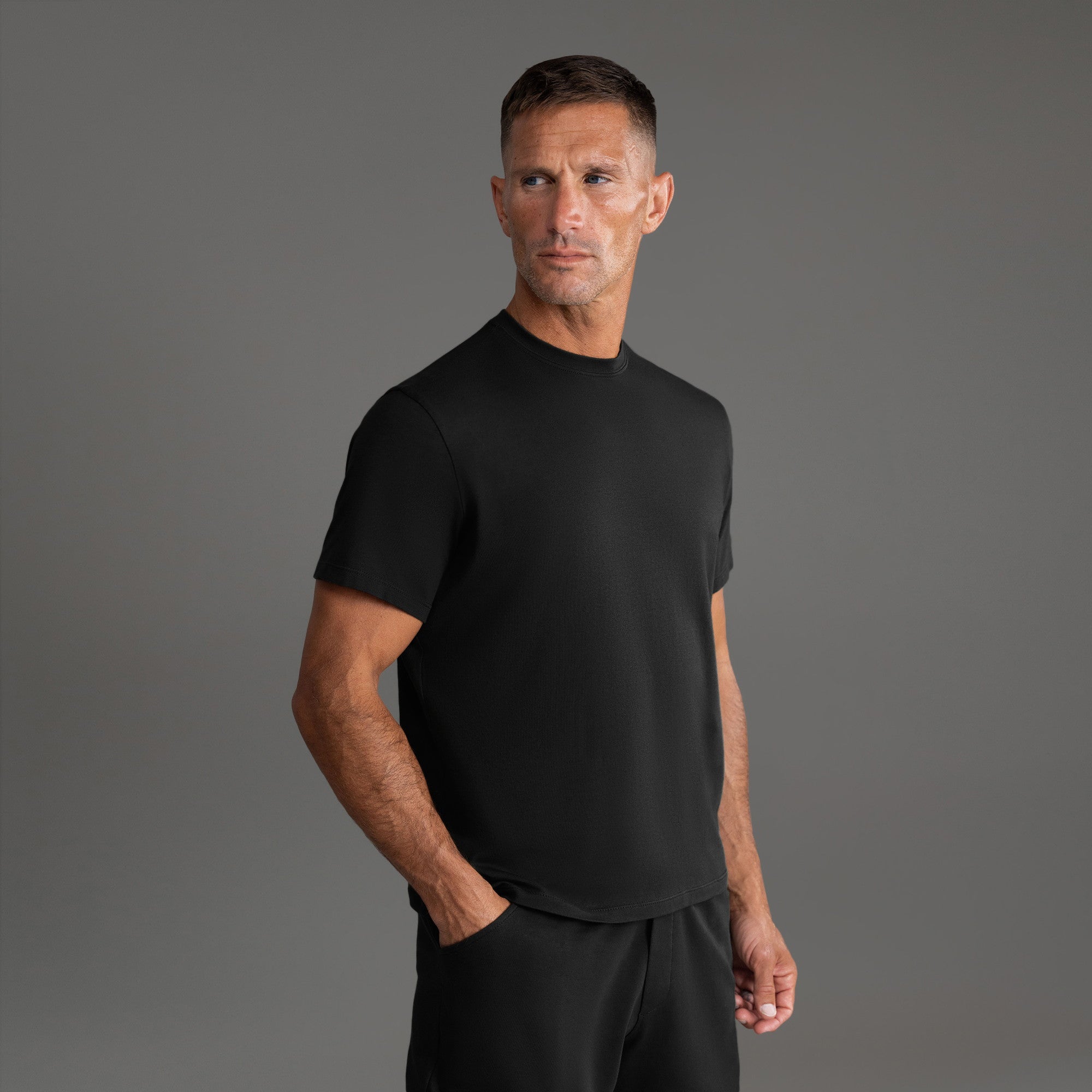 Six t-shirts in Black and White on a beige background model Tyler in Essential