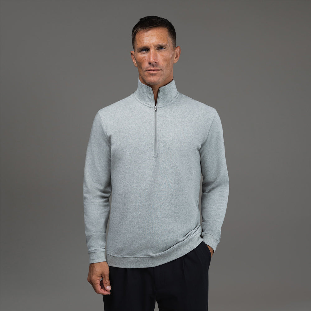 Man wearing a light gray quarter-zip pullover against a gray background.