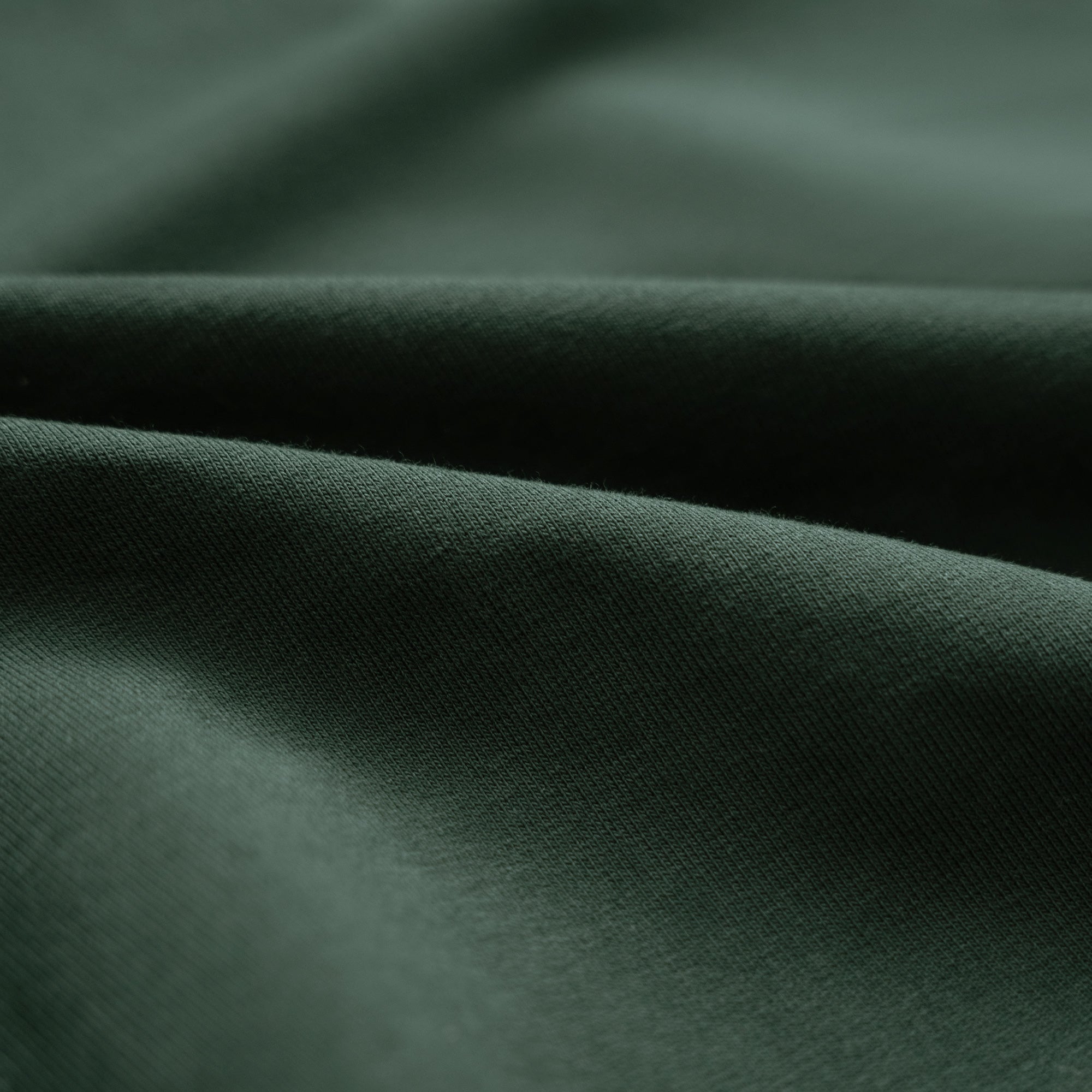 Close-up of dark green fabric folds Cumulus Long Sleeve Terry Polo model Matteo in Pine Grove