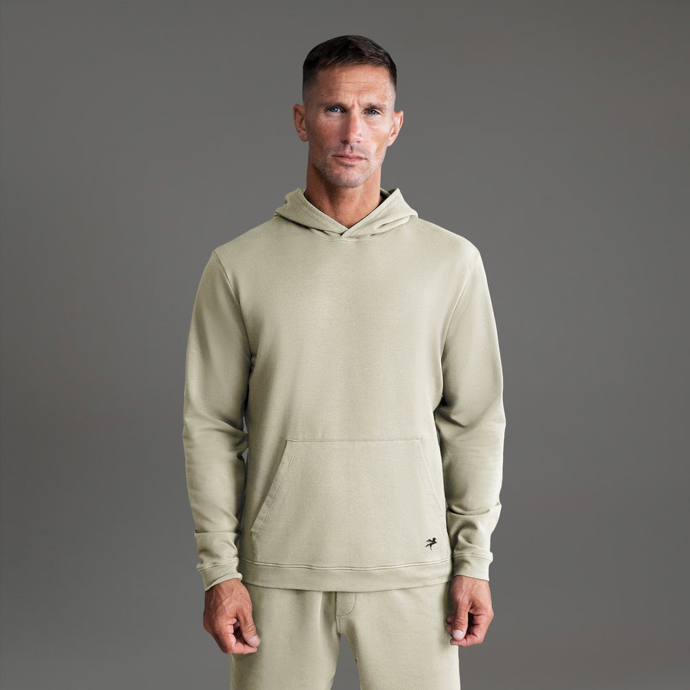 Person wearing a light green hooded sweatshirt against a gray background.