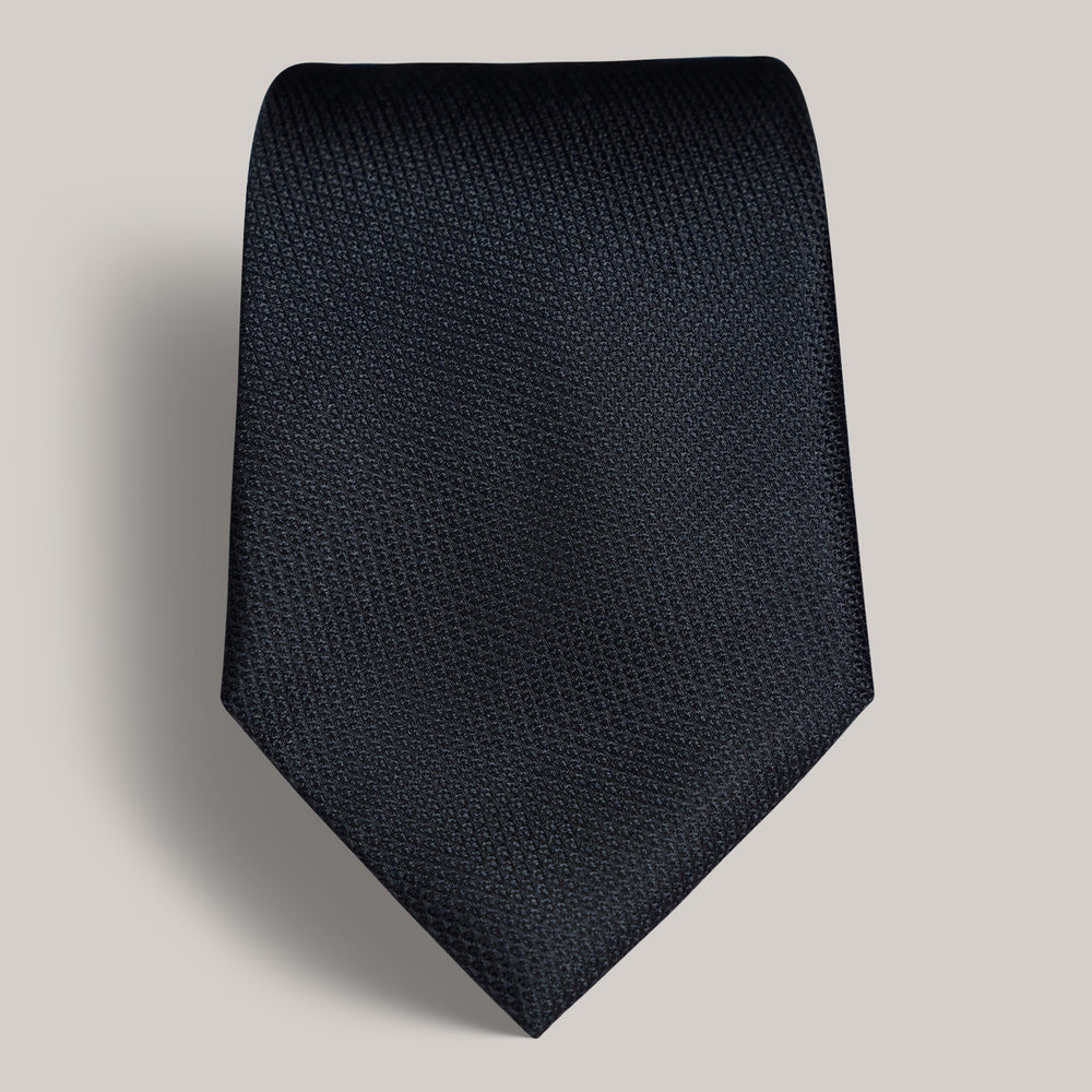 Dark textured necktie on a plain background.