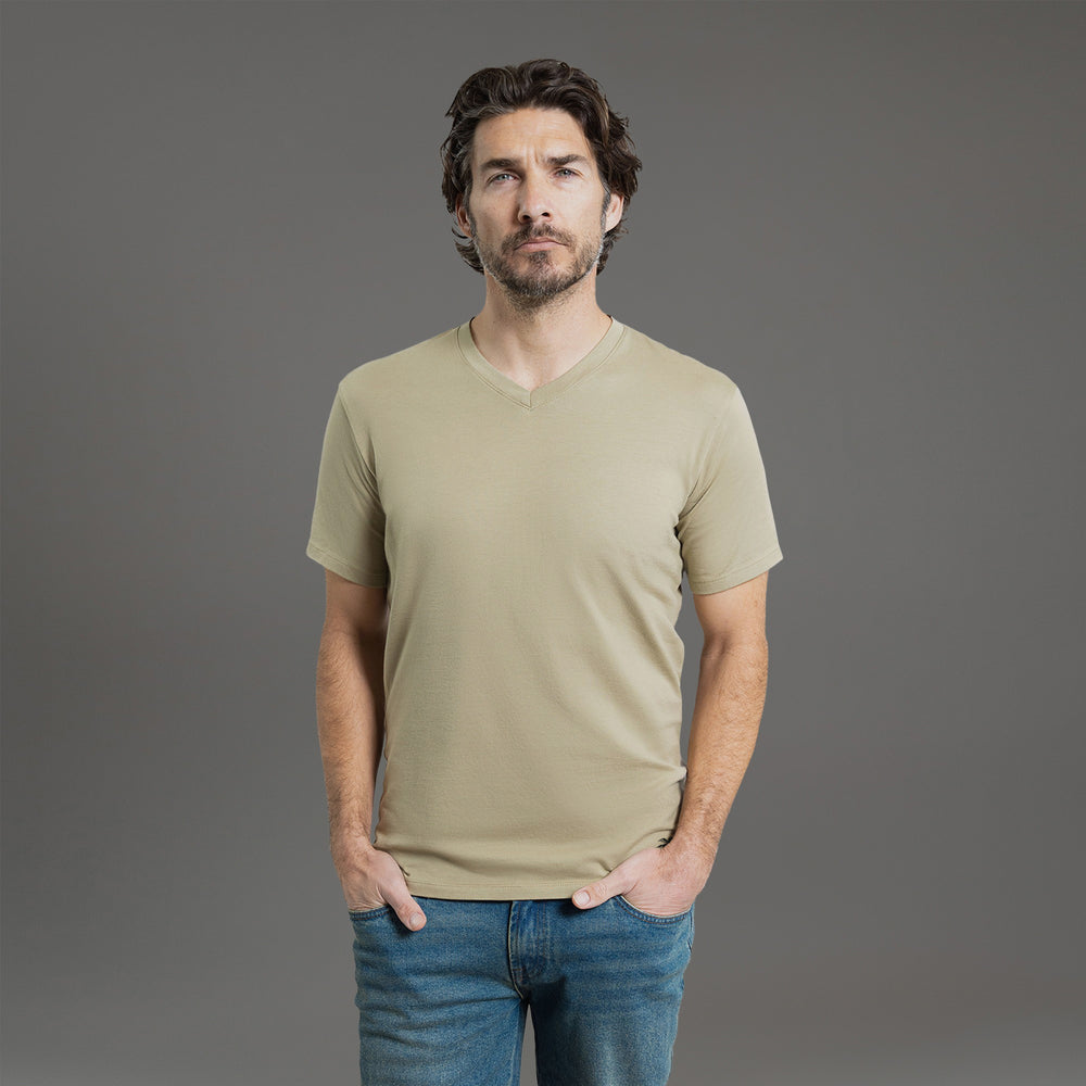 Man wearing a beige V-neck T-shirt against a gray background.