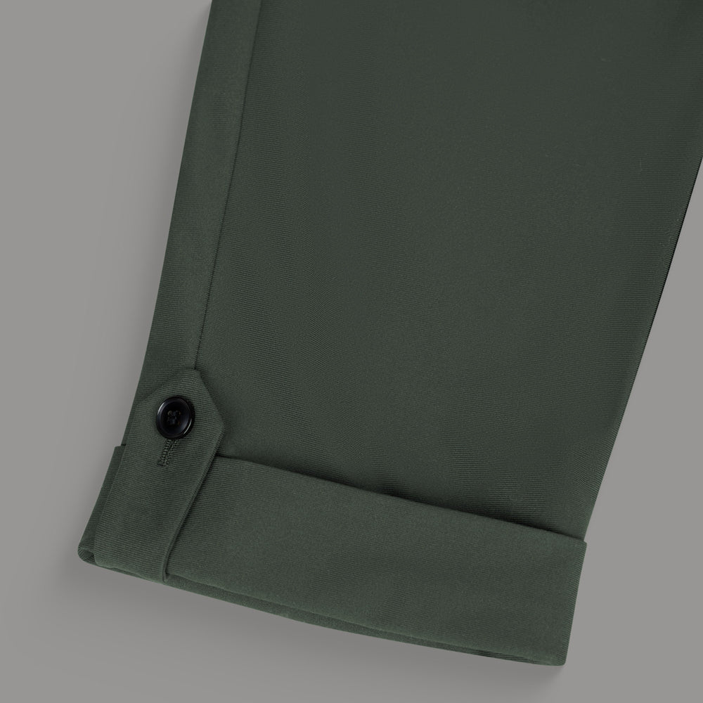 Close-up of a green pant leg with a black button detail.