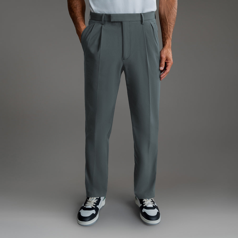 Man wearing pleated gray pants and black-and-white sneakers.