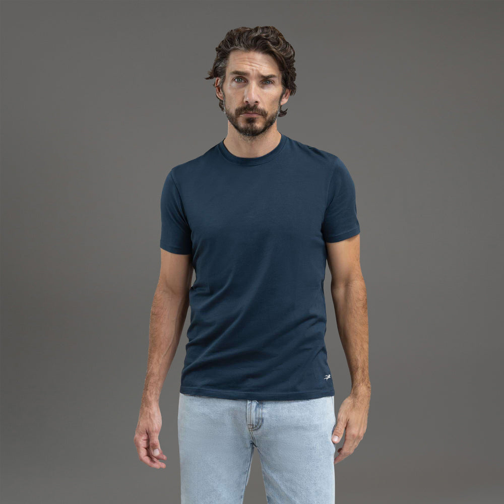 Man wearing a dark blue t-shirt and matching pants against a gray background.