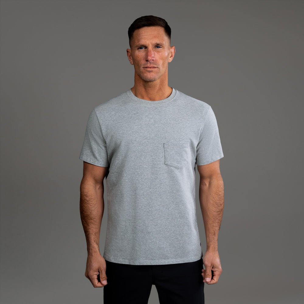 A person wearing a gray t-shirt against a gray background.