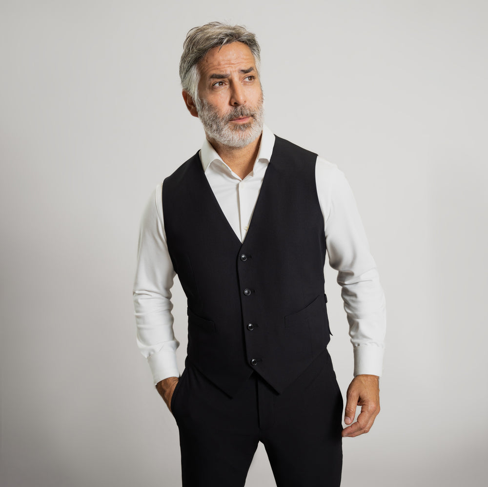 Man in a blue double-breasted suit standing against a grey background.
