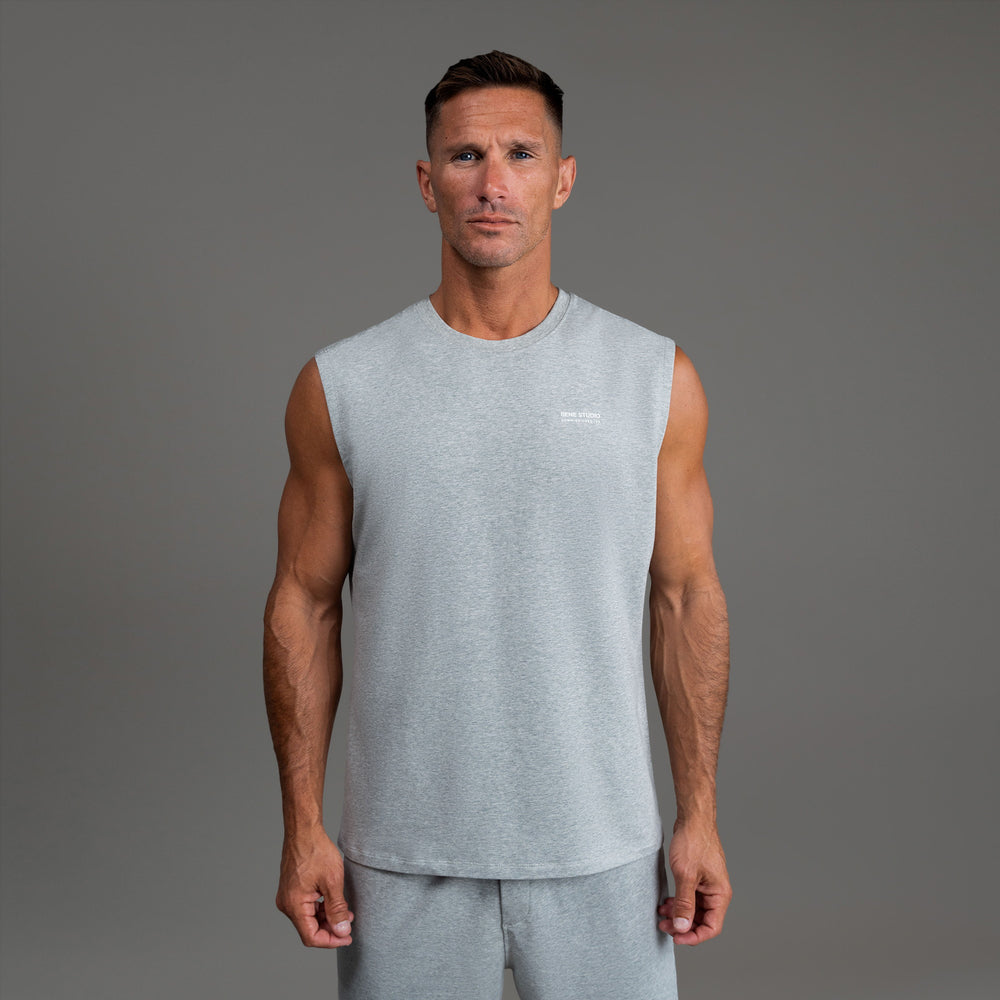 Man in gray sleeveless shirt and shorts standing against a plain background.