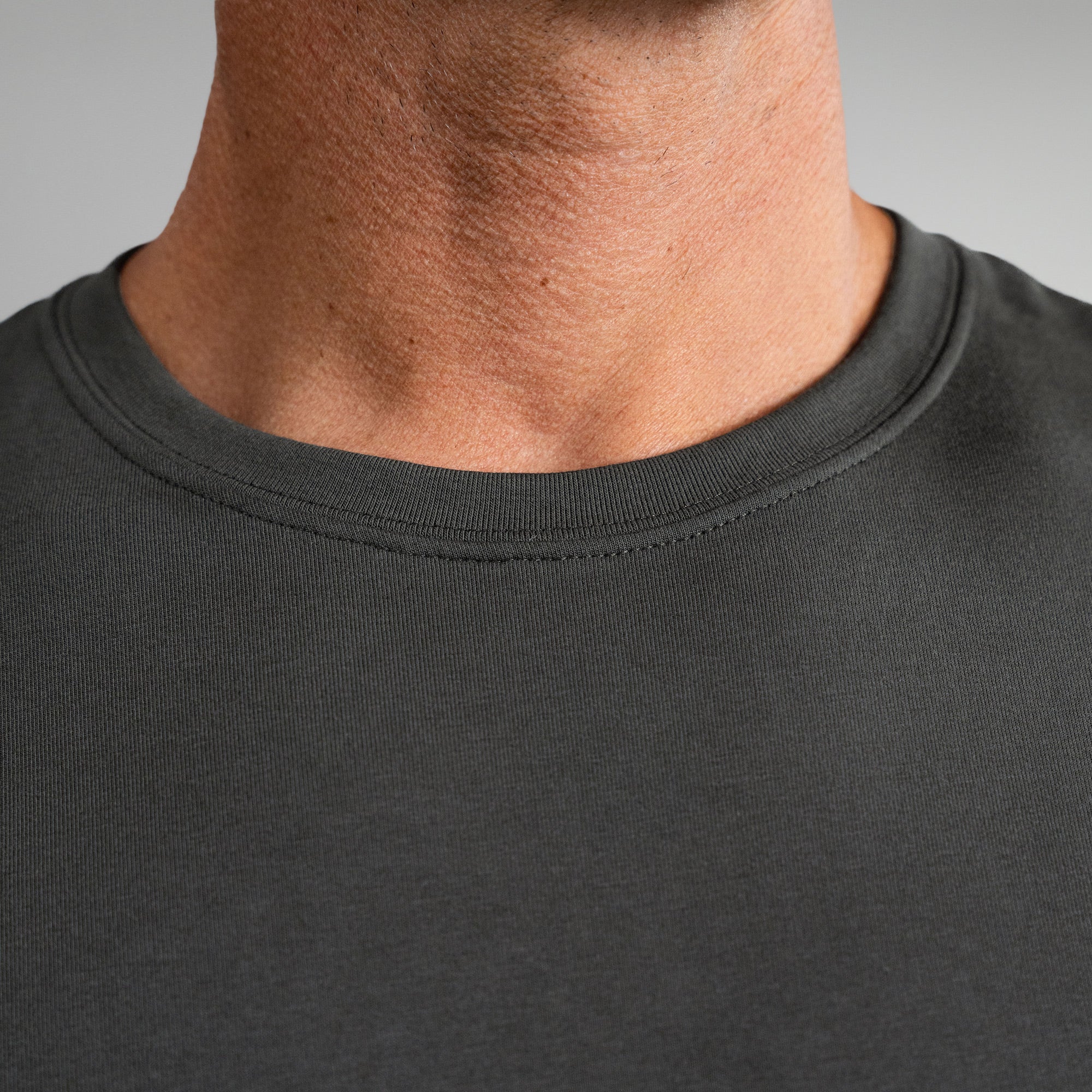 Six t-shirts in Black, Deep Sea, Moss, Umber, Frost Gray, and White on a beige background model Tyler in Best-Seller