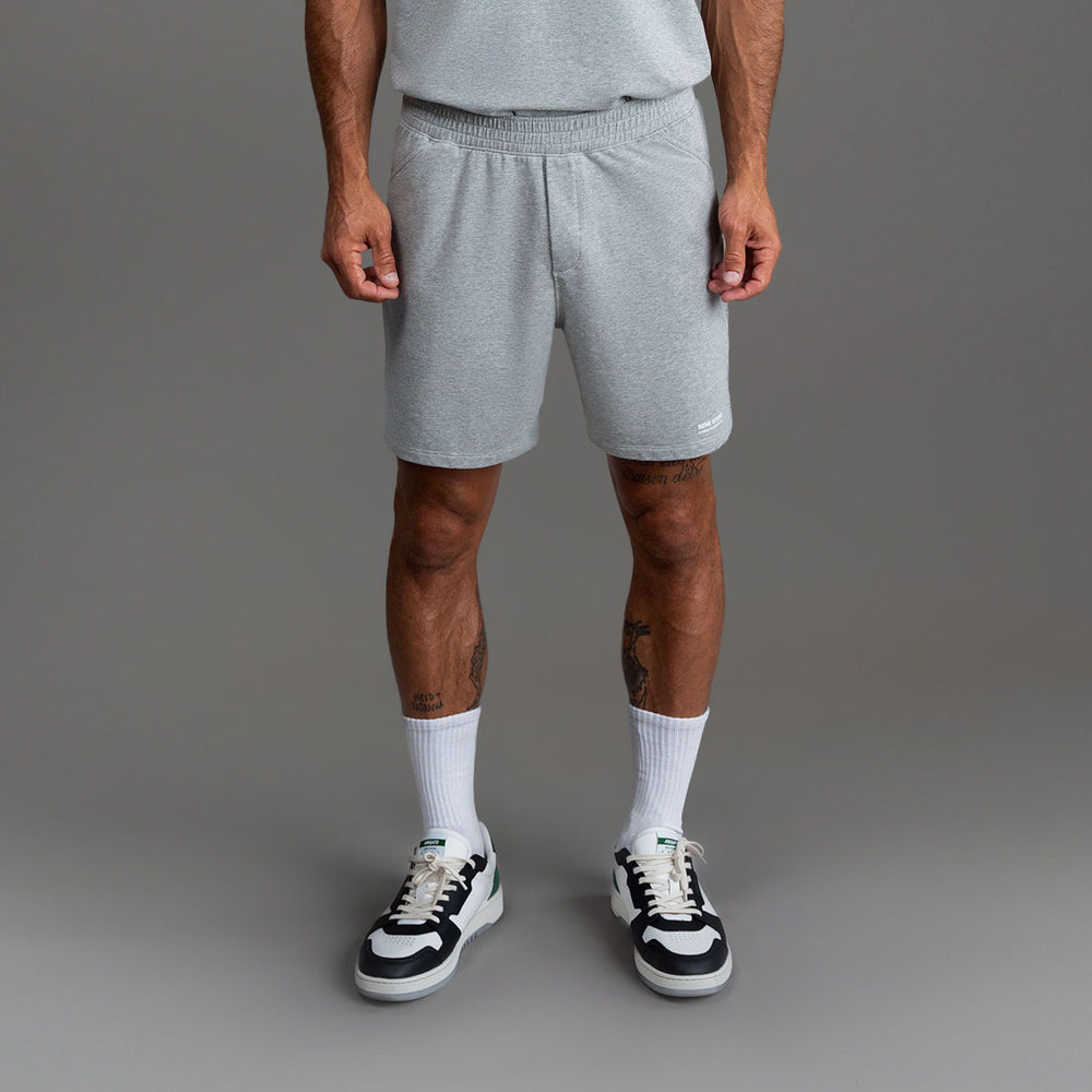 Person in gray shorts and sneakers, standing against a neutral background.