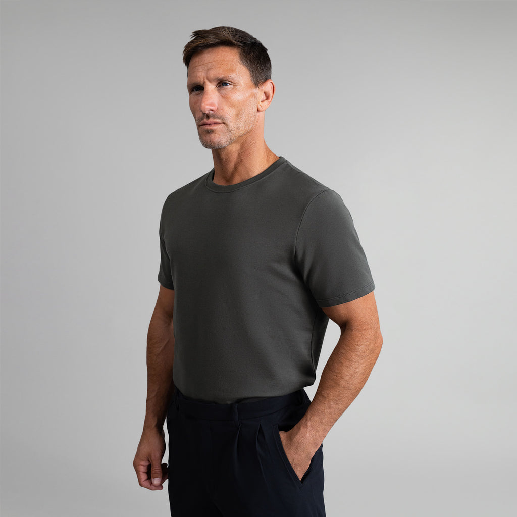 Six t-shirts in Black, Deep Sea, Moss, Umber, Frost Gray, and White on a beige background model Tyler in Best-Seller