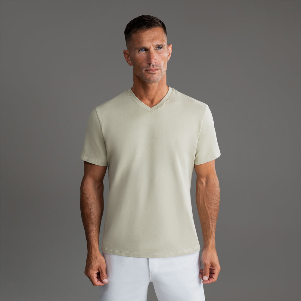 Man wearing a beige V-neck T-shirt against a gray background.