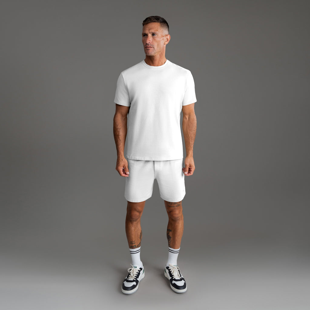 Six t-shirts in Black, Deep Sea, Moss, Umber, Frost Gray, and White on a beige background model Tyler in Best-Seller