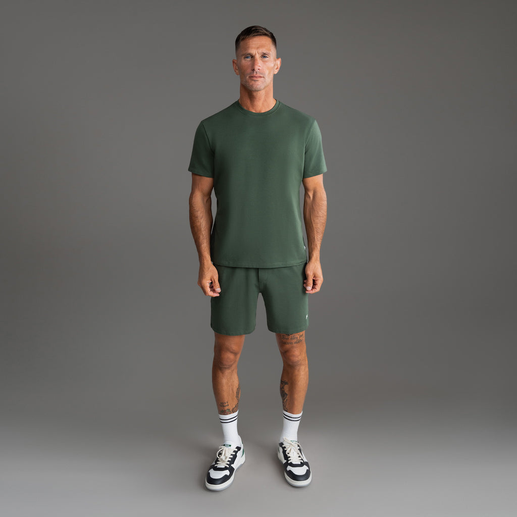 Six t-shirts in Black, Deep Sea, Moss, Umber, Frost Gray, and White on a beige background model Tyler in Best-Seller