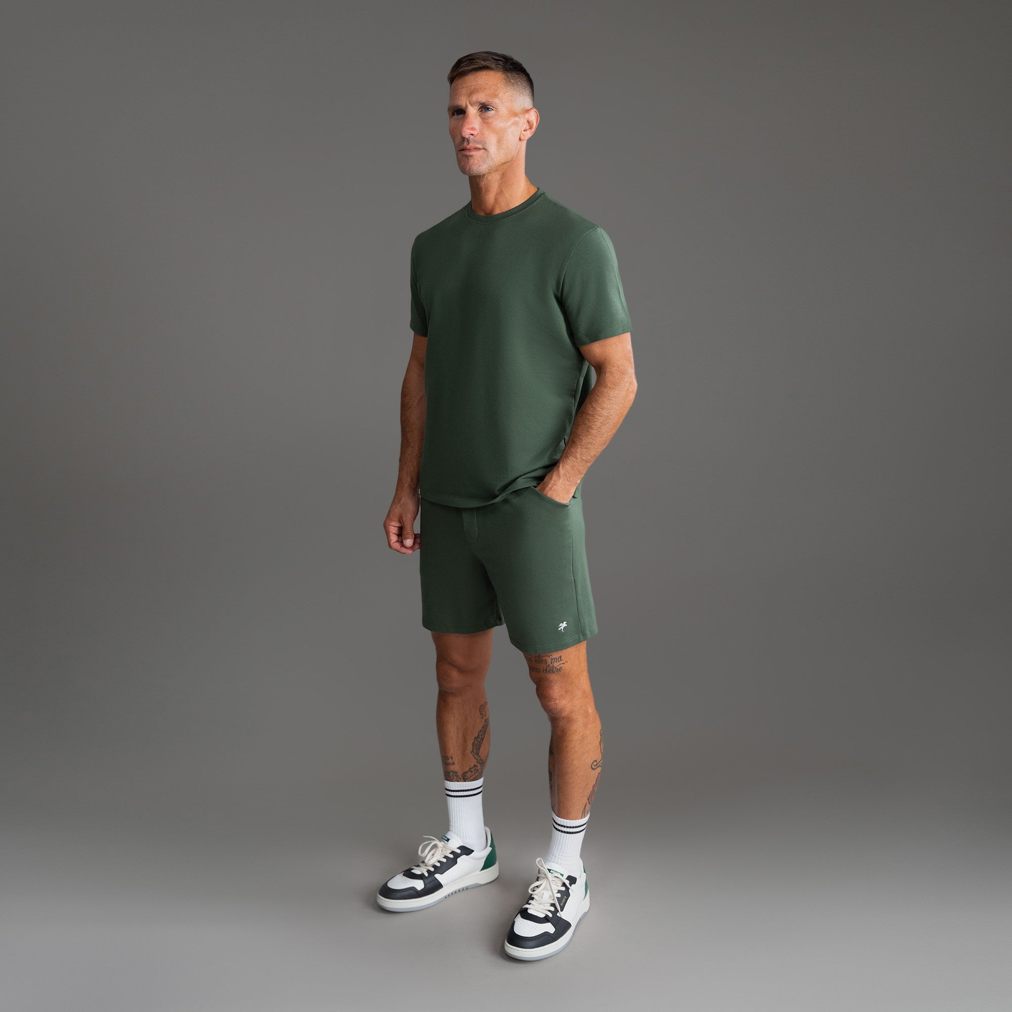 Six t-shirts in Black, Deep Sea, Moss, Umber, Frost Gray, and White on a beige background model Tyler in Best-Seller