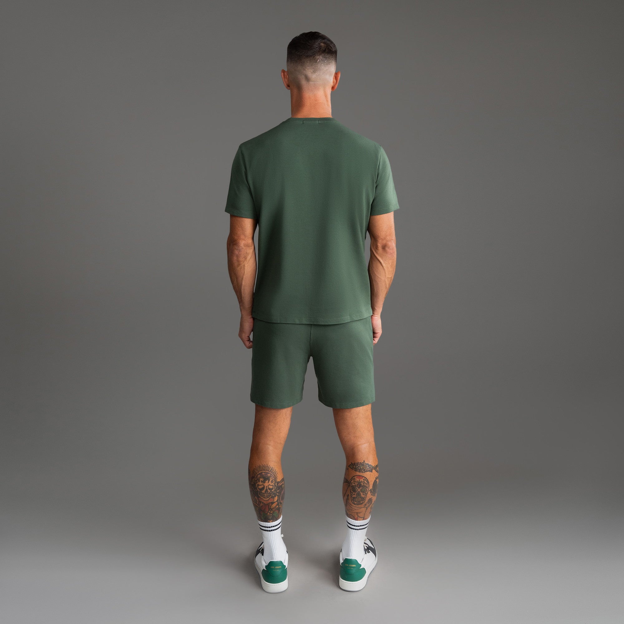 Six t-shirts in Black, Deep Sea, Moss, Umber, Frost Gray, and White on a beige background model Tyler in Best-Seller