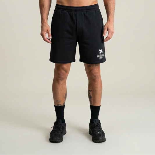 Person wearing black shorts with a logo on a plain background model Tyler in Black
