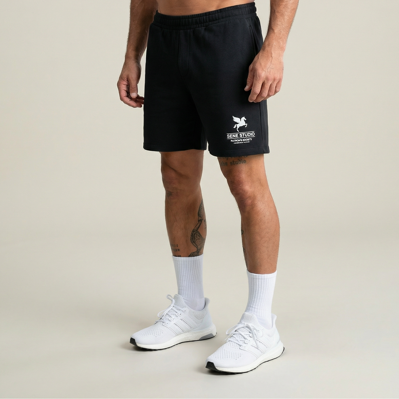 Person wearing black shorts with a logo on a plain background model Tyler in Black