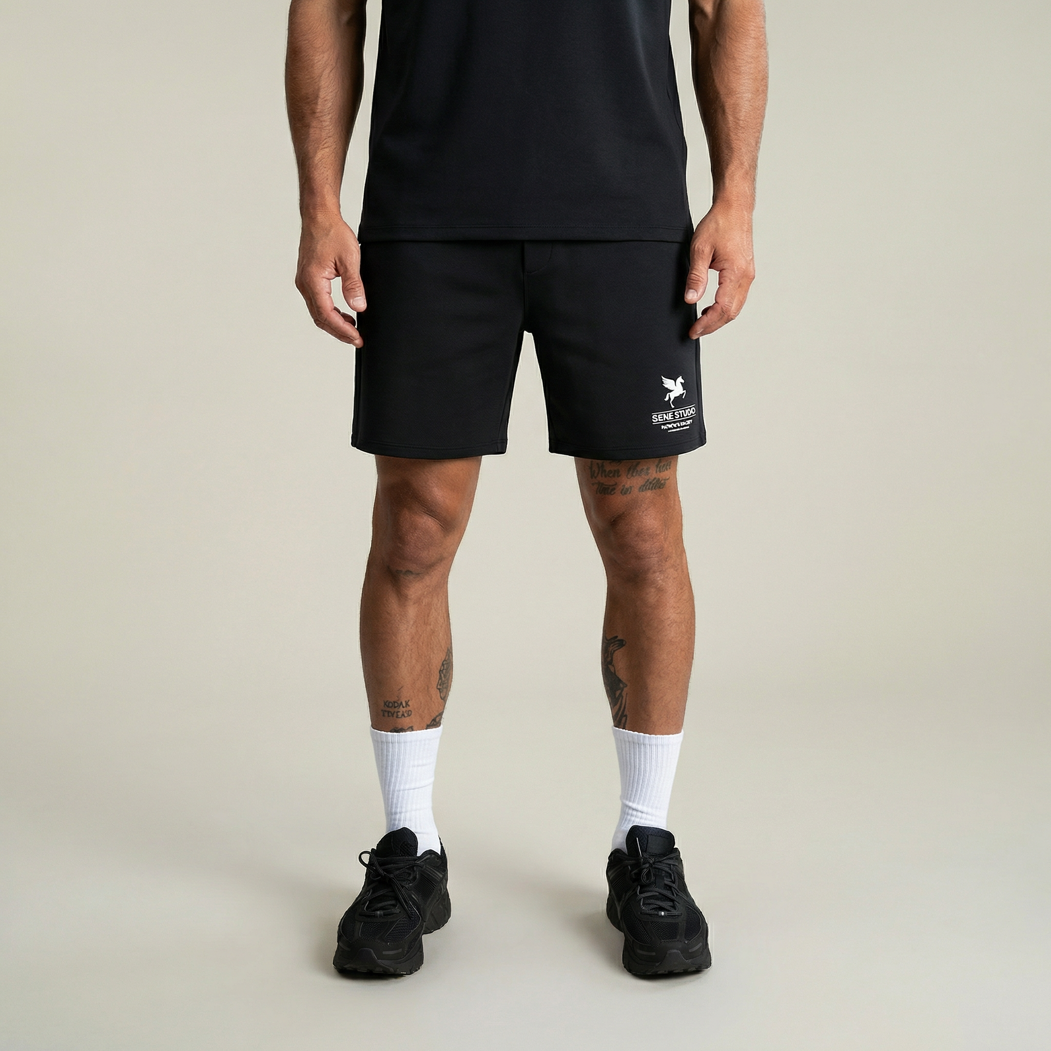Person wearing black shorts with a logo on a plain background model Kive in Black