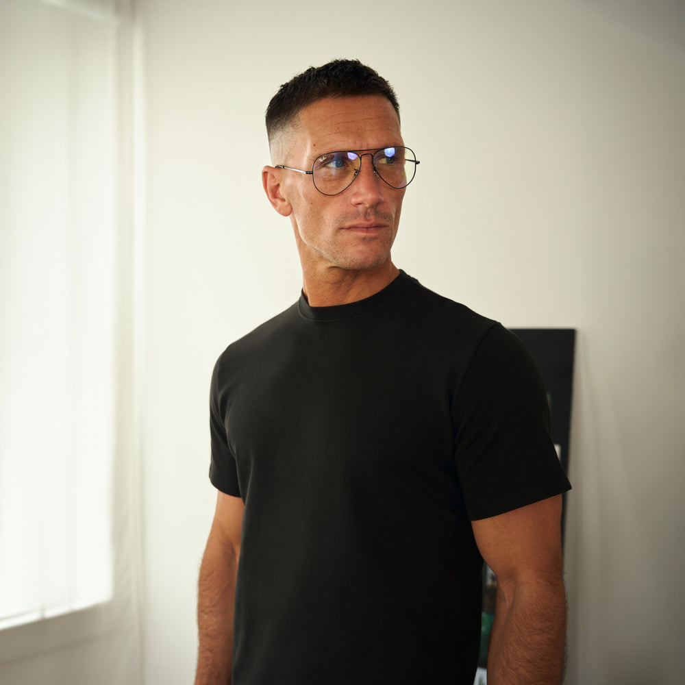 Man in black t-shirt and glasses looking to the side.
