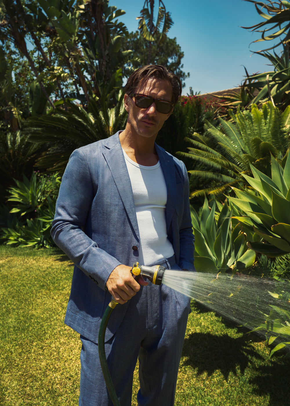 Man in a Sene linen blazer watering the garden