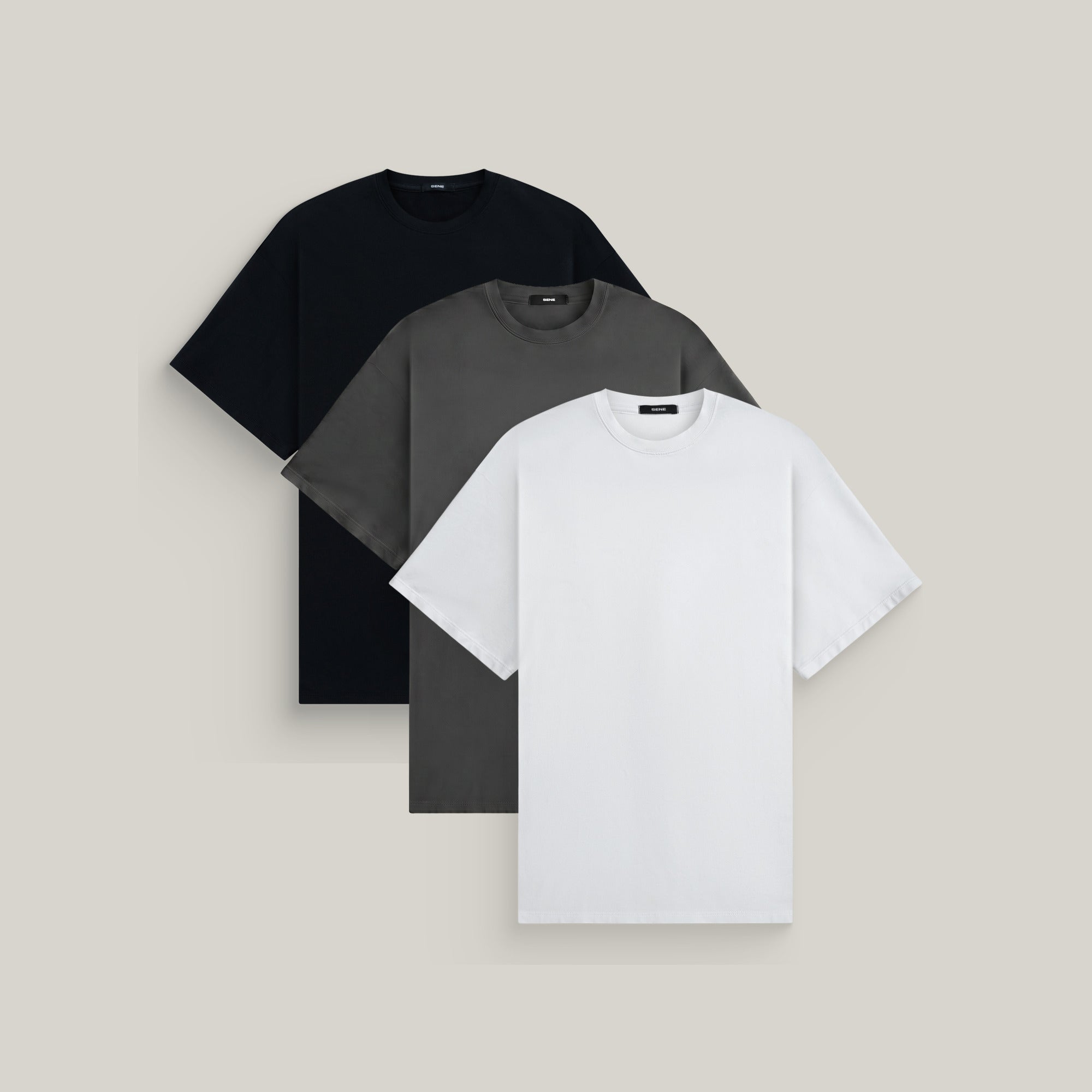 Three oversized t-shirts in black, smoke and white on a beige background model Kive in Minimalist