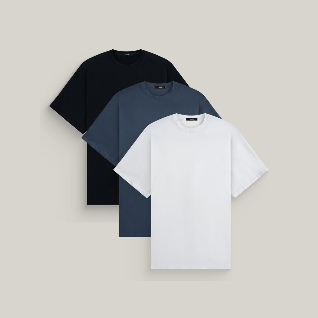 Three oversized t-shirts in black, deep sea and white on a beige background model Kive in Shade