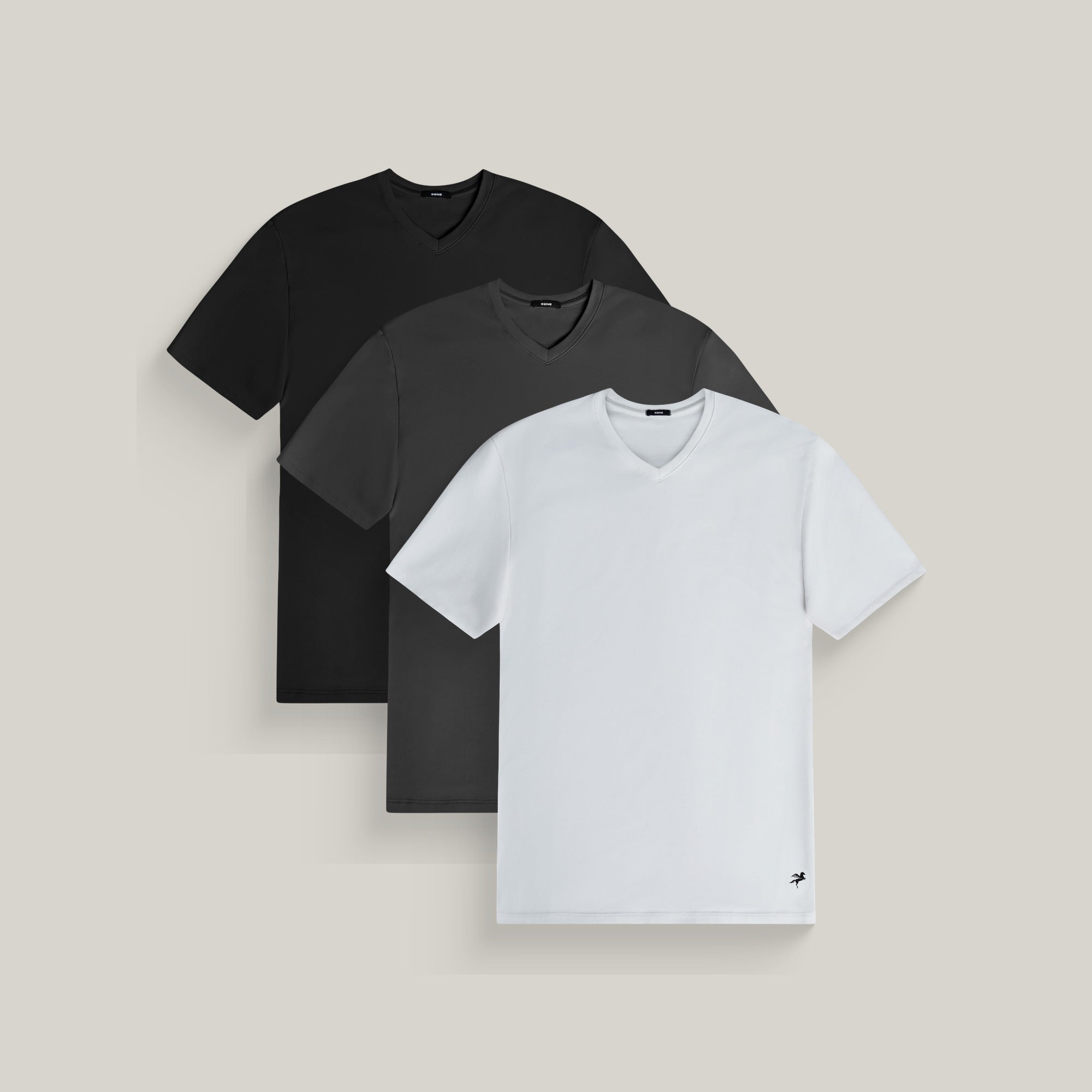 Three v-neck t-shirts in black, smoke and white on a beige background model Tyler in Minimalist