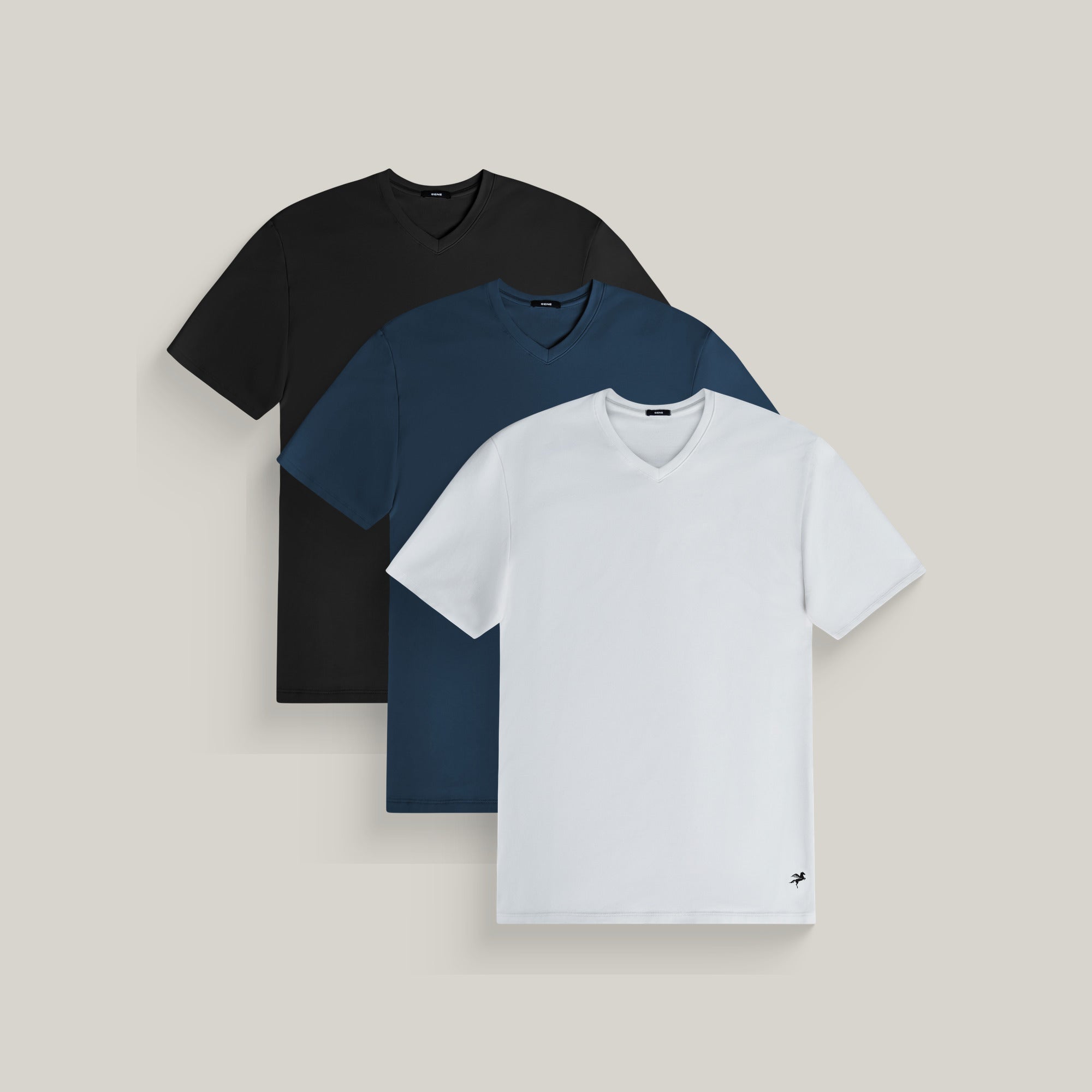 Three v-neck t-shirts in black, deep sea and white on a beige background model Tyler in Shade