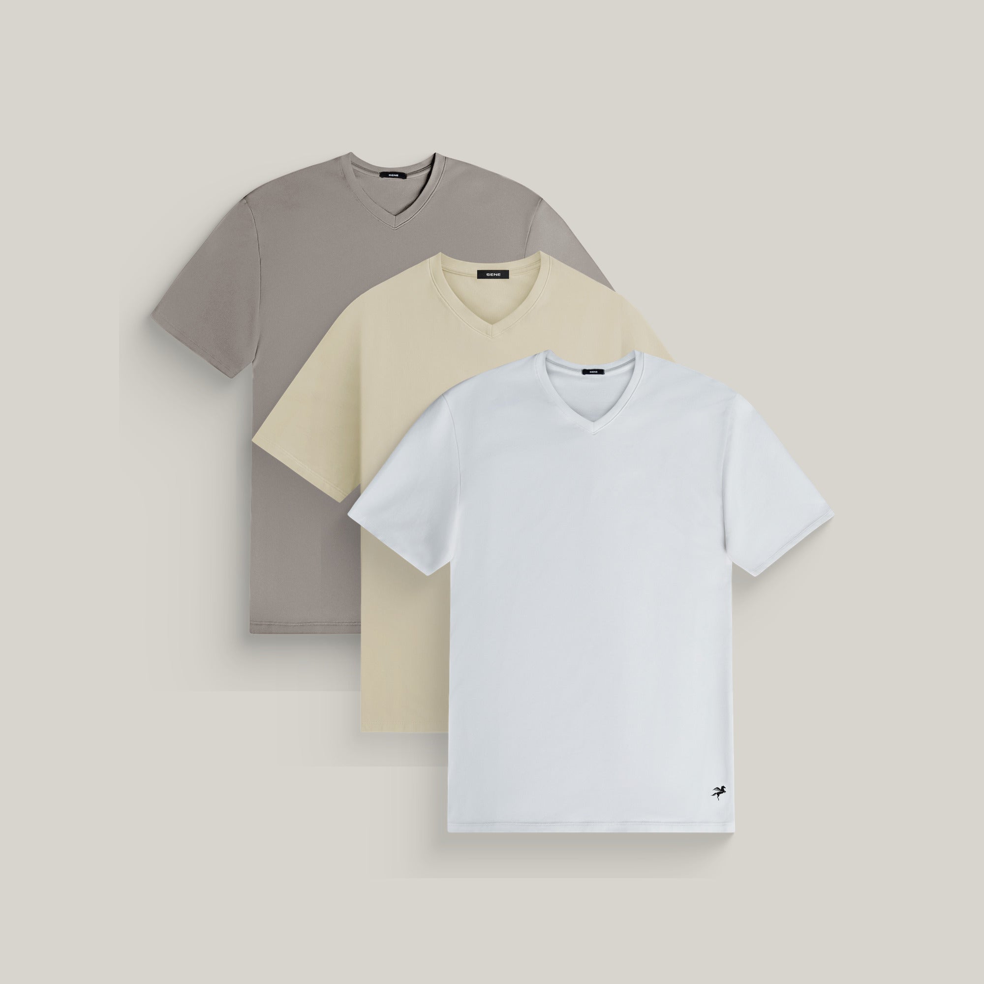 Three v-neck t-shirts in frost gray, villa stone and white on a beige background model Tyler in Shore